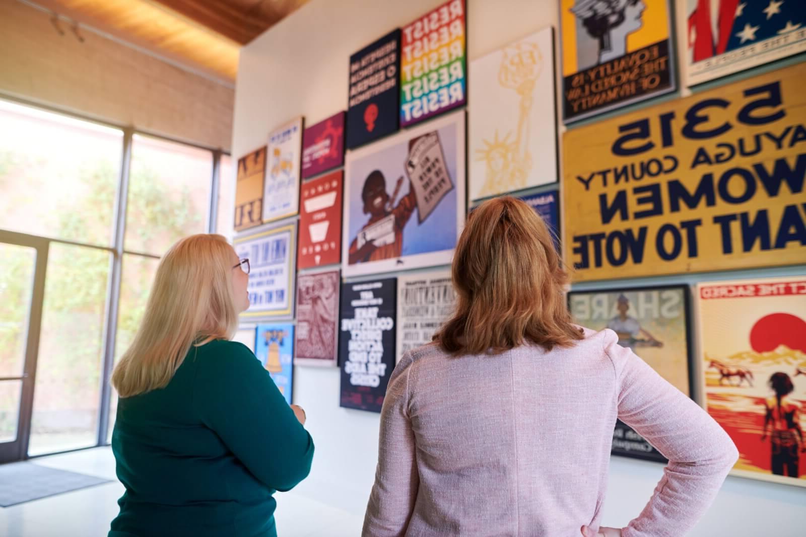 Two women looking at an exhibit of posters at the Equal Rights Heritage Center